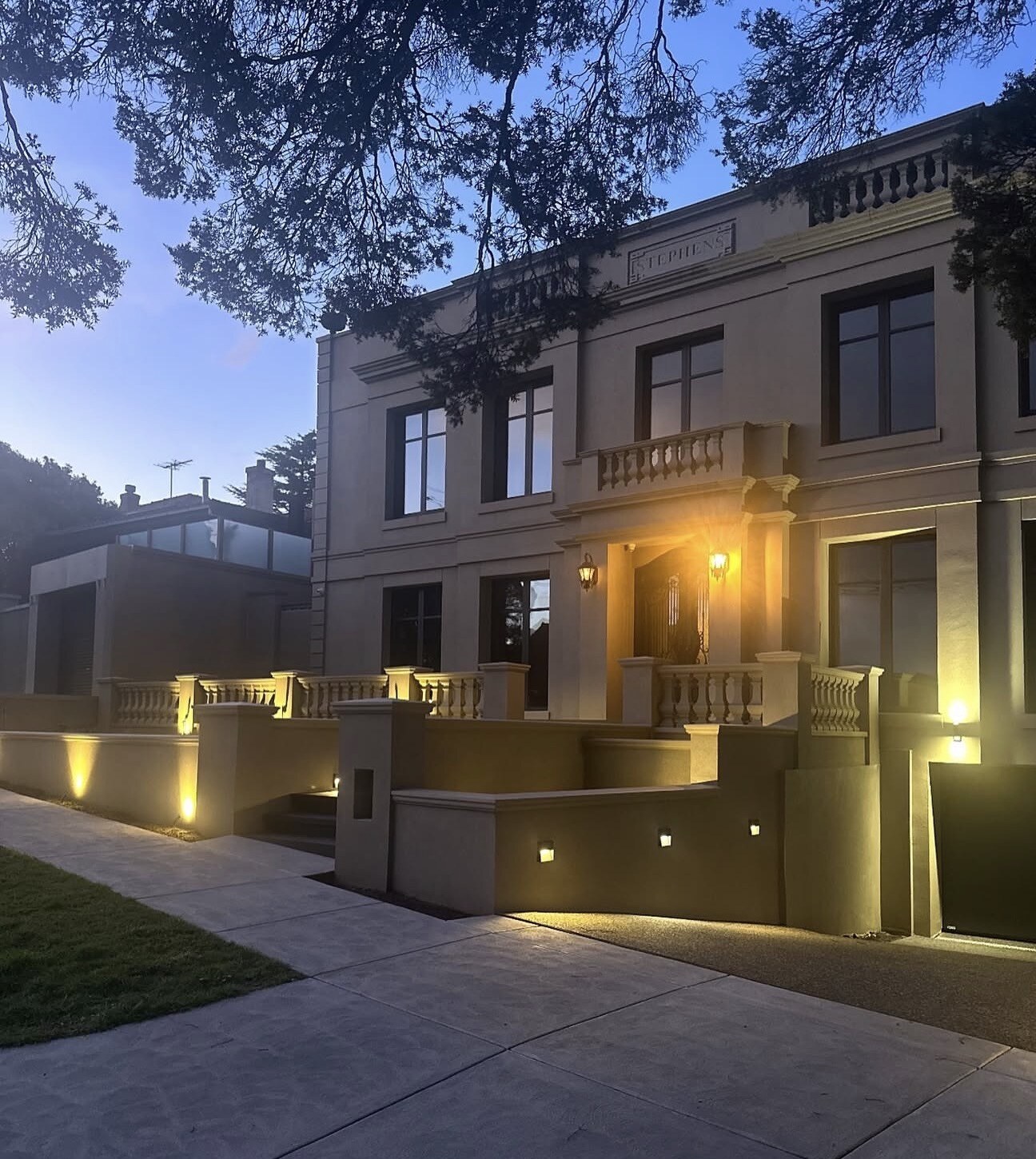House facade and front terrace illuminated by warm outdoor lighting